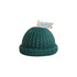 A green candle shaped like a knitted beanie, featuring a small flag with a logo.