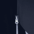 A close-up of a zip on a dark fabric, featuring a silver pull tab against a contrasting background.