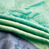 A flannel blanket featuring layers in soft mint green and blue hues. The fabric appears plush and cozy.