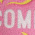 A pink floor mat featuring a textured design with a logo in white and yellow elements.
