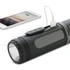 A black, cylindrical flashlight with a USB port for charging devices, alongside a smartphone connected to it.