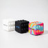 Three Popper Cubes in white, black, and a multicoloured design, featuring a textured surface with raised bumps.
