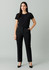 A woman wearing black tapered adjustable waist pants and a black top, standing with hands in pockets against a neutral background.