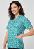 A tunic featuring a teal and white stardust print, with short sleeves and a pocket, displayed on a model.