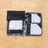 Packing cubes in black and grey arranged inside a suitcase, featuring mesh panels and handles for easy access.