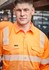 A man wearing an orange work shirt with segmented reflective tape and a logo on the front.