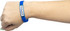 A blue silicon wristband on a wrist, featuring a logo on an attached rectangular plaque.