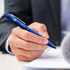 A blue metal pen is being held in a hand, with a document partially visible in the background. The pen has a logo.