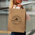 A large brown paper bag with flat handles and a logo displayed prominently.