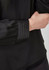 A black long sleeve blouse featuring gathered sleeves and a sleek finish. It has subtle pleated detailing at the cuffs.