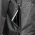 A close-up view of a black windbreaker jacket featuring a zippered pocket with a smartphone inside.