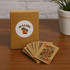 A deck of eco-friendly playing cards in brown packaging with a logo, showcasing several cards with colourful designs.