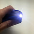A blue 360 Degree Torch held in a hand, emitting a bright light from its front end.