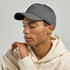 A grey cap with a curved brim, featuring a logo, worn by a person in a light-coloured hoodie.