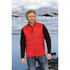 A man wearing a red thermal vest over a black long-sleeve shirt, standing by a glacial landscape.
