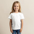 A child in a white T-shirt stands smiling against a neutral background. The shirt has a logo.