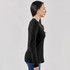 A woman is wearing a black Ashburn crew neck shirt, viewed from the side, with long sleeves and a fitted silhouette.