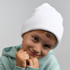 A white beanie made from recycled polyester, worn by a smiling child in a green hoodie.