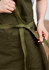 An olive green apron with a tied waist strap, featuring pockets and a textured fabric.