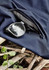 A pair of black sunglasses rests on navy lightweight shorts with a zippered pocket, placed on a textured surface.