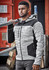 A man wearing a black and grey striped unisex reinforced knit hoodie, holding a metal ladder against a red backdrop.