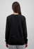 A black long sleeve women's tee, showing the back view and paired with light grey pants. The shirt has a logo.