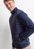 A men's tailor jacket in navy blue, featuring a quilted front and side pockets, worn by a smiling model.