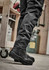 A pair of black rugged cooling stretch pants paired with black boots, set in an industrial environment.