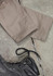 A pair of beige cargo pants laid out flat next to a black boot on a textured surface.