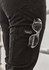 A close-up of black cargo pants with a logo and clear sunglasses tucked into the pocket.