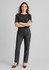 A woman stands confidently in black women's comfort wool stretch relaxed pants and a matching top, with a logo visible.