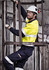 A man wearing a hi-vis yellow and navy work shirt, climbing a metal ladder, with protective gear and glasses.