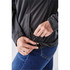 A close-up of a dark grey women's anorak with a drawstring adjustment at the hem, worn over blue jeans.