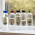 A drink bottle collection featuring five clear Tritan bottles with coloured caps in blue, red, black, and green.