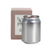 A silver can candle beside a light pink box, featuring a logo on the packaging.