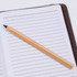 A bamboo pen resting on a lined notebook page, featuring a simple and natural design.