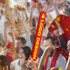Bright red cheerstick with yellow text, set against an energetic crowd celebrating. The stick features a logo.