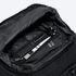 An open black backpack interior featuring a pen, a cardholder, and a small notebook.