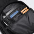 A black backpack interior featuring compartments for a passport, notepad, pens, and a phone. It includes a logo.