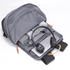 A grey Fairweather Backpack open to reveal a laptop, headphones, and a rolled blanket inside. It has a logo.