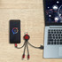 A round-shaped, light-up multi charging cable in black, connected to a smartphone and laptop on a wooden surface.