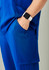 Blue straight leg scrub pant featuring pockets, worn with a watch on the wrist.