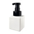 A square white foaming soap dispenser with a black pump top. Features a logo on the front.