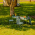 A green cooler box with an attached table and two chairs, set on grass with drinks and snacks around it.