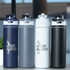 A drink bottle collection featuring navy, grey, white, and black recycled stainless steel with flip straw lids and branding.