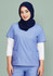 A woman wearing a light blue scrub top with two pockets, layered over a white long-sleeve shirt, and a navy hijab.