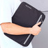 A laptop sleeve in black with a grey zipper, featuring a logo, held under someone's arm.