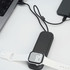 A black foldable charging cable with a wireless watch charger, connected to a laptop and a phone, next to a white watch.