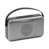 A premium wireless speaker in silver and black, featuring a handle and perforated metal design for enhanced sound.