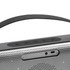 A wireless speaker in grey with a sleek design, featuring control buttons and a logo on the front.